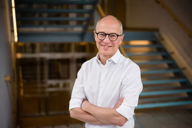 Hans Olsson står med armarna i kors och tittar in i kameran. 