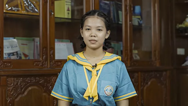 En ung person i blå- och gul skoluniform. 